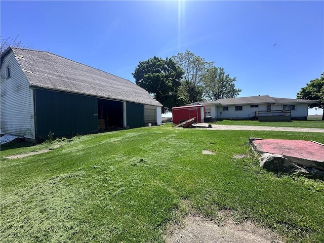 view of green lawn with an outdoor structure, a detached garage, and a pole building