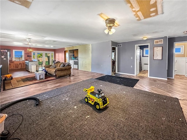 living room featuring ceiling fan, baseboards, and wood finished floors