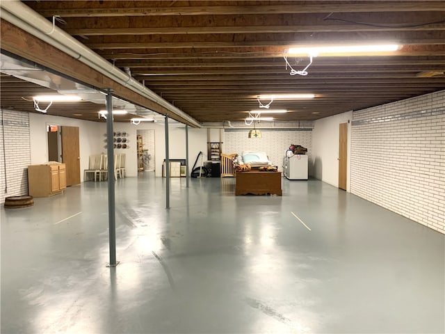 basement featuring independent washer and dryer and brick wall