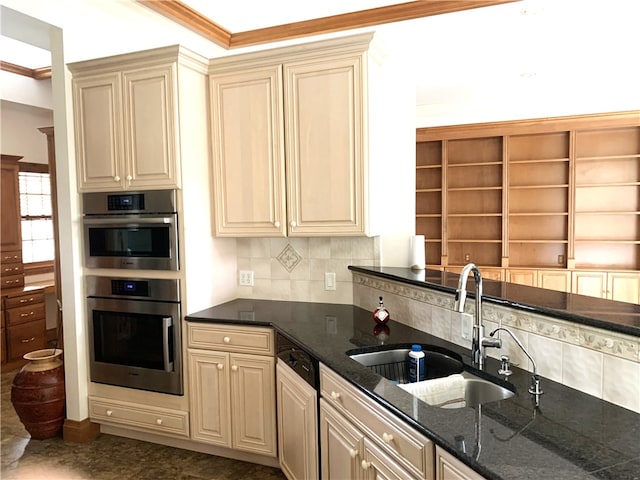 kitchen featuring stainless steel double oven, dark stone counters, sink, and cream cabinetry