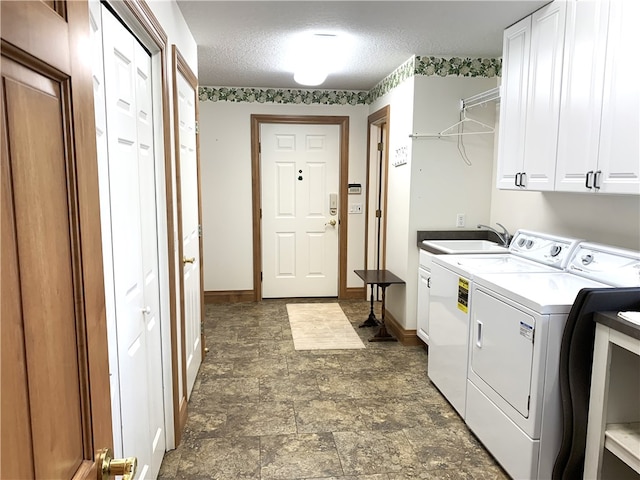 laundry room featuring independent washer and dryer, sink, cabinets, and a textured ceiling