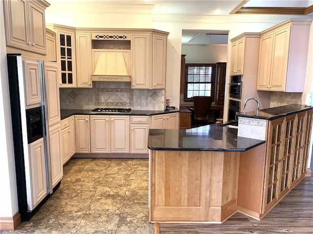 kitchen with refrigerator with ice dispenser, premium range hood, stainless steel gas cooktop, decorative backsplash, and dark stone counters