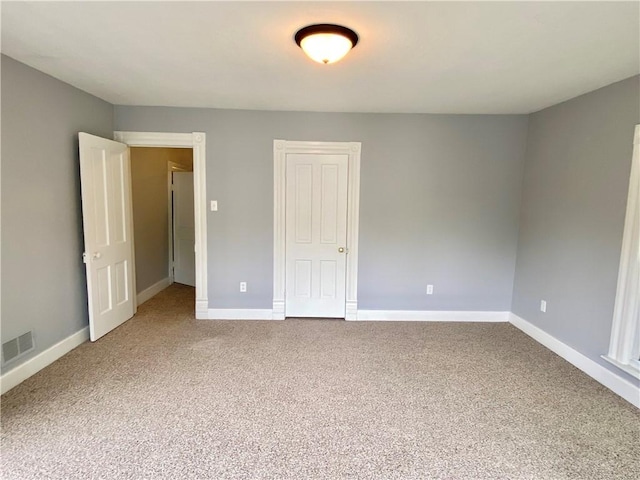 empty room featuring carpet flooring, visible vents, and baseboards