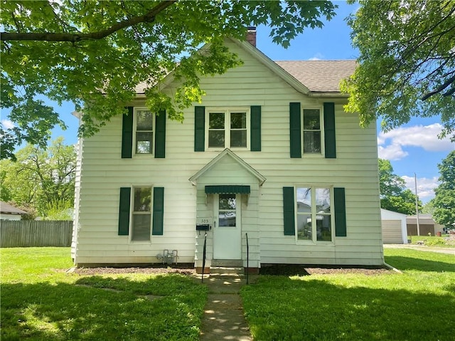 colonial-style house featuring fence, roof with shingles, a chimney, and a front yard