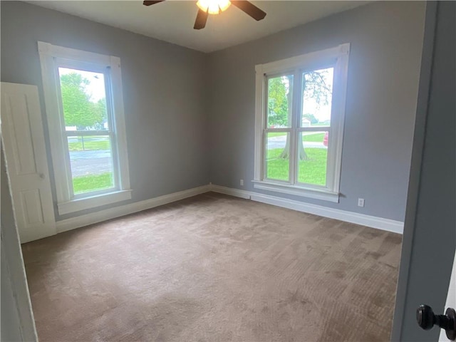 spare room featuring carpet, a ceiling fan, and a healthy amount of sunlight