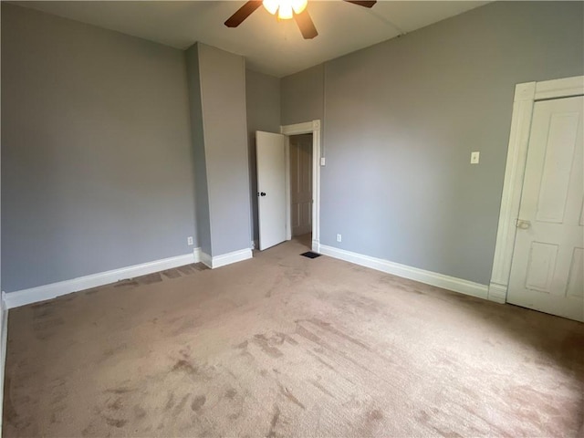 unfurnished bedroom featuring light colored carpet, baseboards, and a ceiling fan