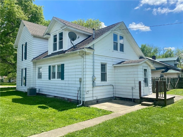 rear view of house with a lawn, a patio area, cooling unit, and a shingled roof