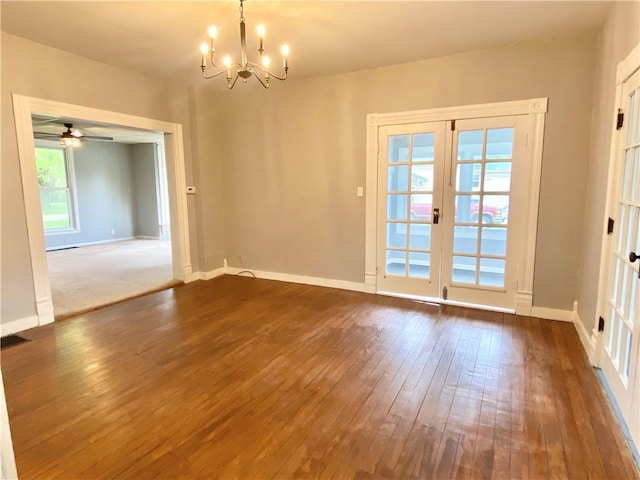 empty room featuring dark wood finished floors, baseboards, and ceiling fan with notable chandelier