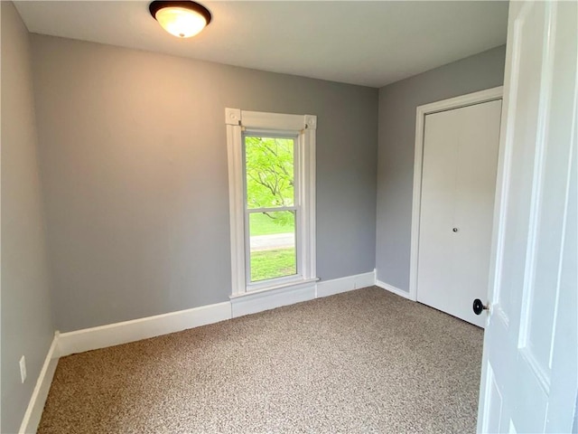 unfurnished room with carpet and baseboards