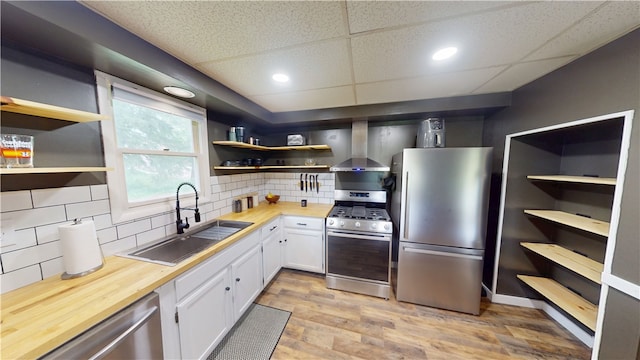 1006 Chicago Ave, Danville, IL 61832 - kitchen with appliances with stainless steel finishes, wall chimney range hood, open shelves, a sink, and white cabinetry