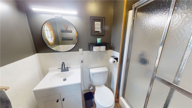 1006 Chicago Ave, Danville, IL 61832 - bathroom with tile walls, toilet, vanity, a stall shower, and a wainscoted wall