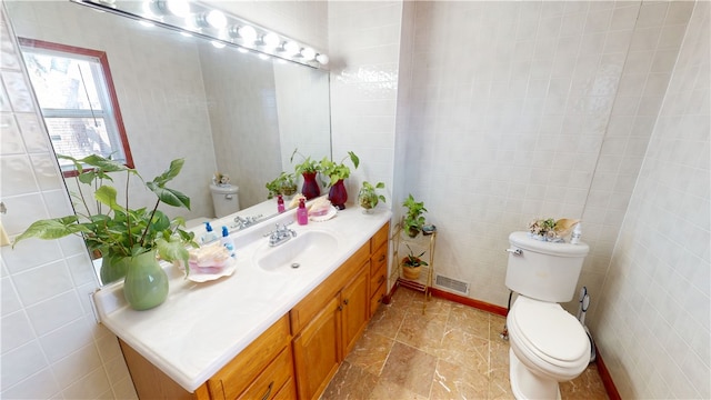 bathroom featuring tile walls, visible vents, vanity, and toilet