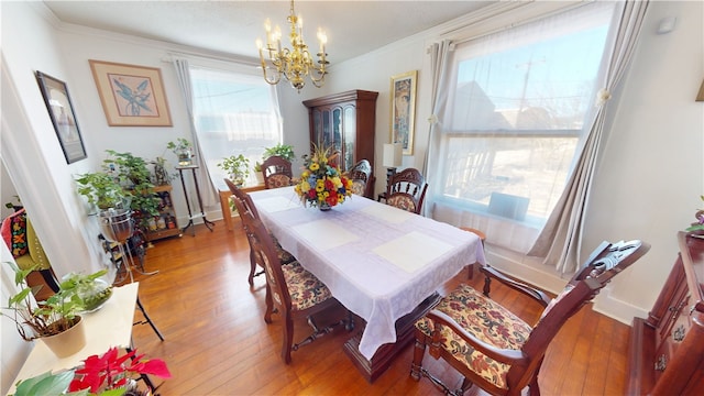 dining area with a chandelier, baseboards, crown molding, and hardwood / wood-style floors