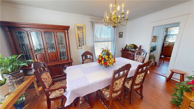 dining room with a chandelier, wood finished floors, and crown molding