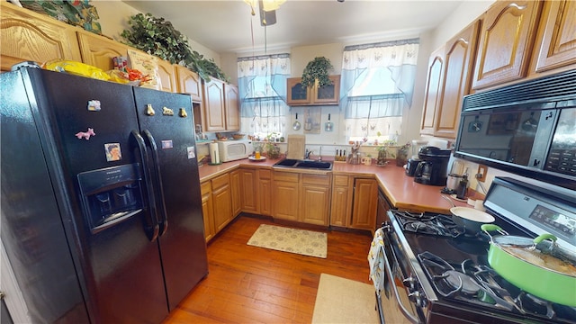 kitchen featuring light countertops, a sink, black appliances, and hardwood / wood-style flooring