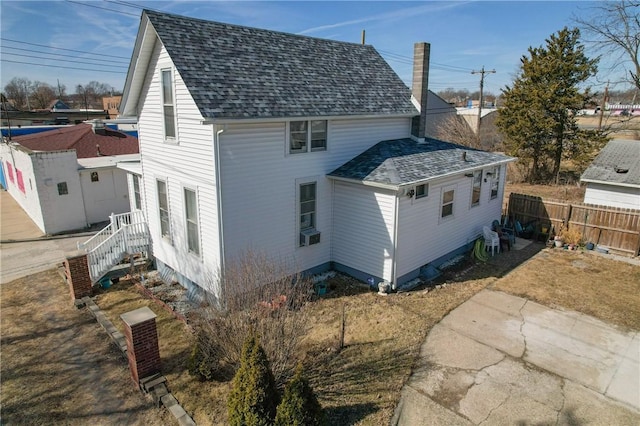 back of property featuring fence and roof with shingles