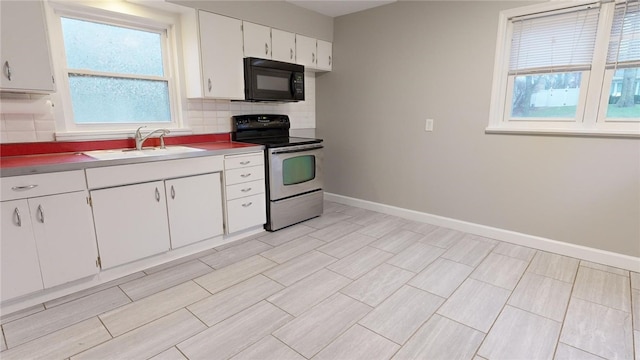 kitchen with backsplash, a sink, stainless steel range with electric stovetop, black microwave, and baseboards