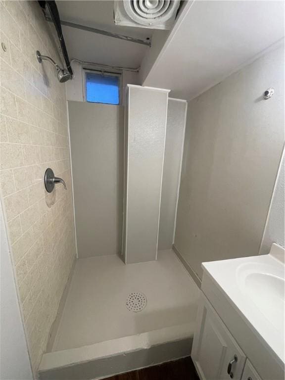 full bathroom featuring a tile shower and vanity