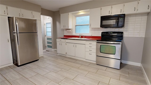 kitchen featuring stainless steel appliances, a sink, white cabinetry, and decorative backsplash