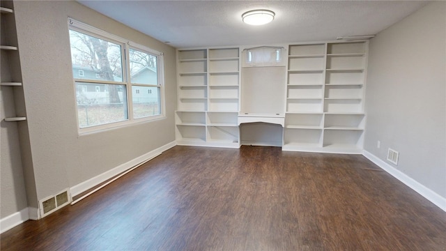 interior space with baseboards, a textured ceiling, visible vents, and wood finished floors