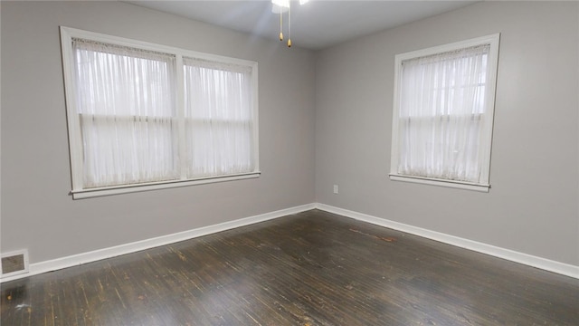 spare room featuring hardwood / wood-style floors, a ceiling fan, visible vents, and baseboards