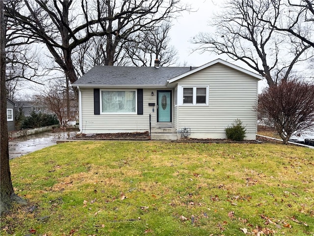 view of front of property with entry steps, a shingled roof, and a front yard