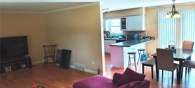 living room with sink, crown molding, dark wood-type flooring, and a chandelier