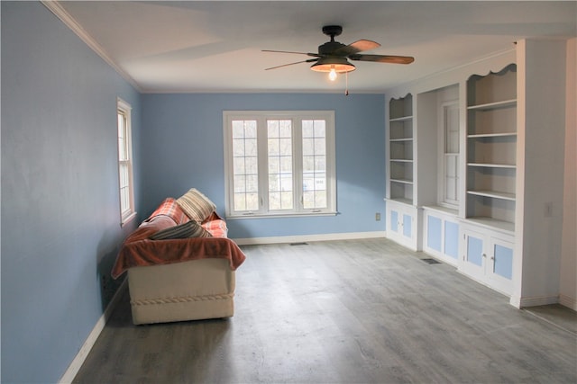 unfurnished room featuring built in shelves, hardwood / wood-style flooring, ceiling fan, and ornamental molding