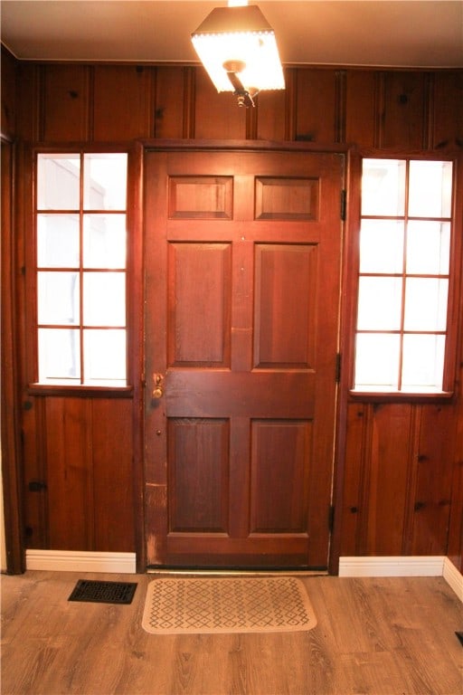 doorway to outside featuring wood-type flooring and wood walls