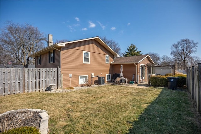 rear view of property with a chimney, fence, cooling unit, and a yard