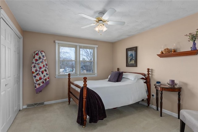 bedroom with a closet, visible vents, light carpet, ceiling fan, and baseboards