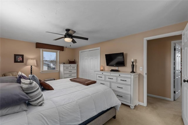 bedroom with a ceiling fan, a closet, light colored carpet, and baseboards