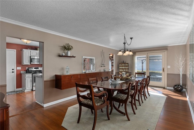 dining space featuring baseboards, wood finished floors, crown molding, a textured ceiling, and a notable chandelier