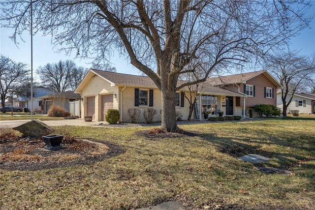 view of front of house with an attached garage, driveway, a front yard, and brick siding