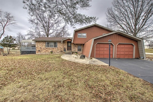 split level home with a garage, driveway, brick siding, and a front lawn