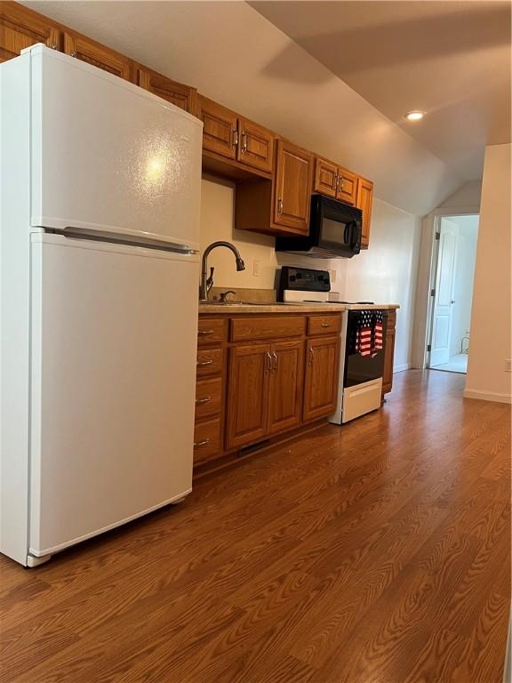 kitchen with lofted ceiling, sink, white appliances, and dark hardwood / wood-style floors