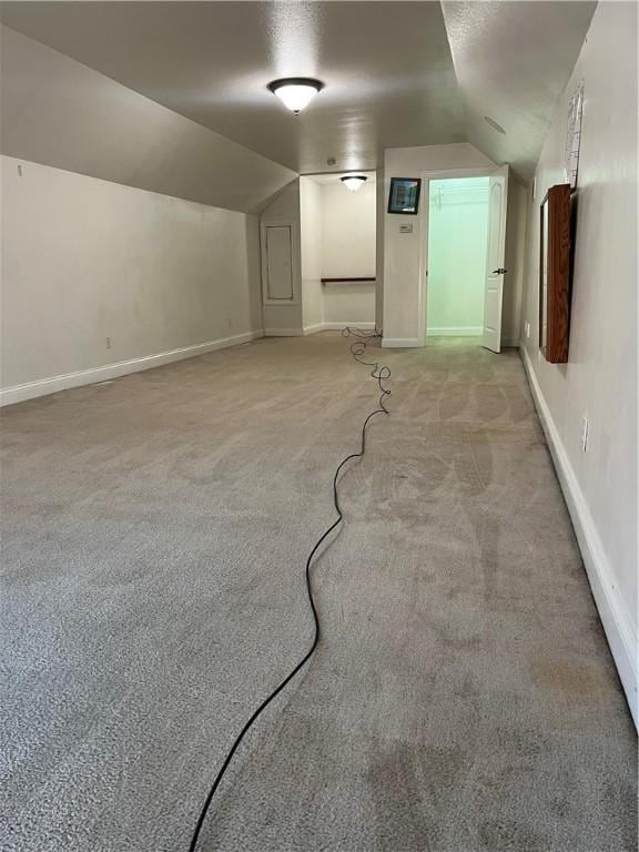 additional living space featuring light colored carpet and lofted ceiling