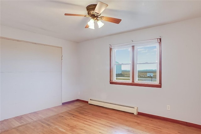 unfurnished room featuring ceiling fan, light hardwood / wood-style flooring, and a baseboard heating unit