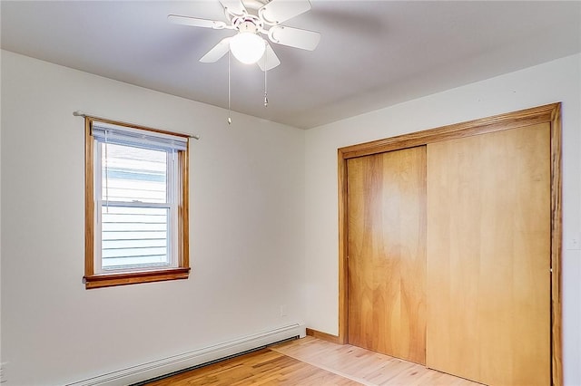 unfurnished bedroom featuring light hardwood / wood-style floors, a closet, ceiling fan, and baseboard heating