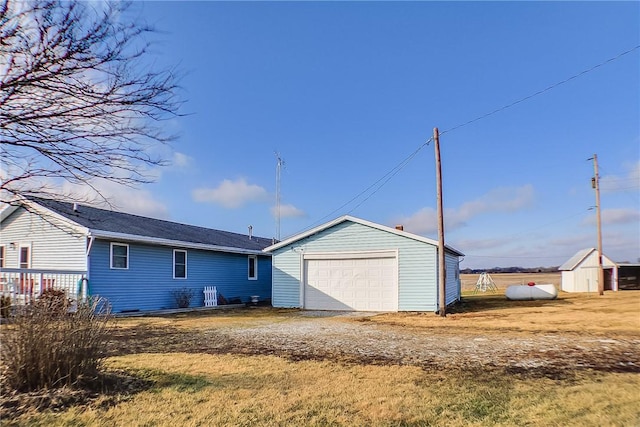 rear view of property with a garage and a storage unit