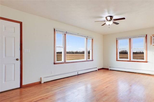 unfurnished room with a baseboard radiator, a healthy amount of sunlight, and light hardwood / wood-style flooring