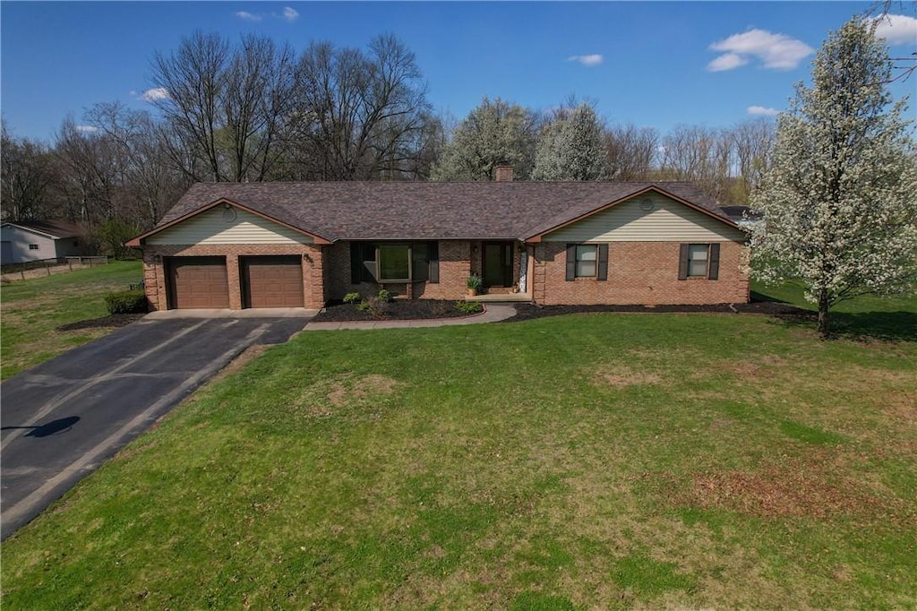 ranch-style house featuring a chimney, a front lawn, aphalt driveway, brick siding, and a garage
