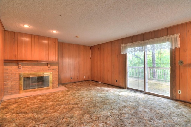 2290 N Kenwood Ct, Decatur, IL 62526 - unfurnished living room featuring carpet flooring, wood walls, a textured ceiling, and a fireplace