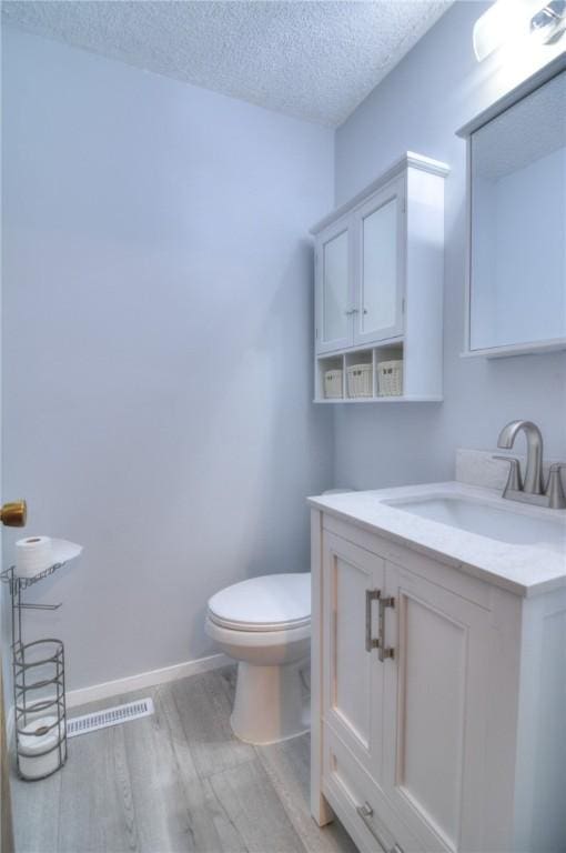 2290 N Kenwood Ct, Decatur, IL 62526 - bathroom with wood finished floors, toilet, vanity, a textured ceiling, and baseboards