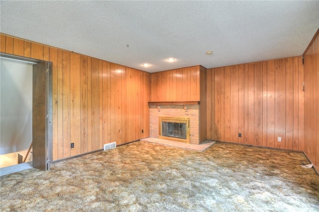 2290 N Kenwood Ct, Decatur, IL 62526 - unfurnished living room with carpet flooring, a fireplace, wooden walls, and a textured ceiling