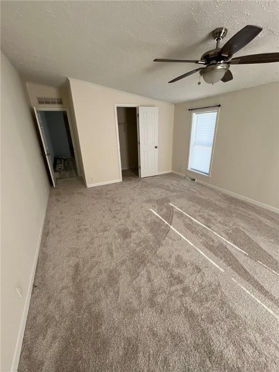 unfurnished bedroom featuring visible vents, a closet, baseboards, a textured ceiling, and carpet flooring
