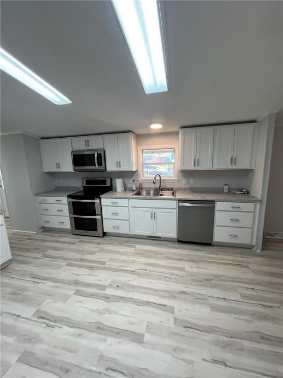 kitchen featuring light countertops, a sink, white cabinets, and stainless steel appliances