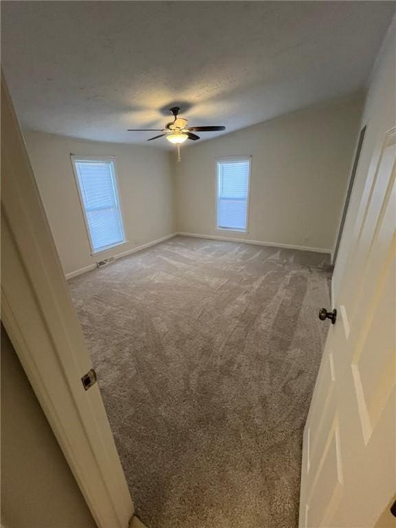 unfurnished room featuring baseboards, ceiling fan, visible vents, and light colored carpet