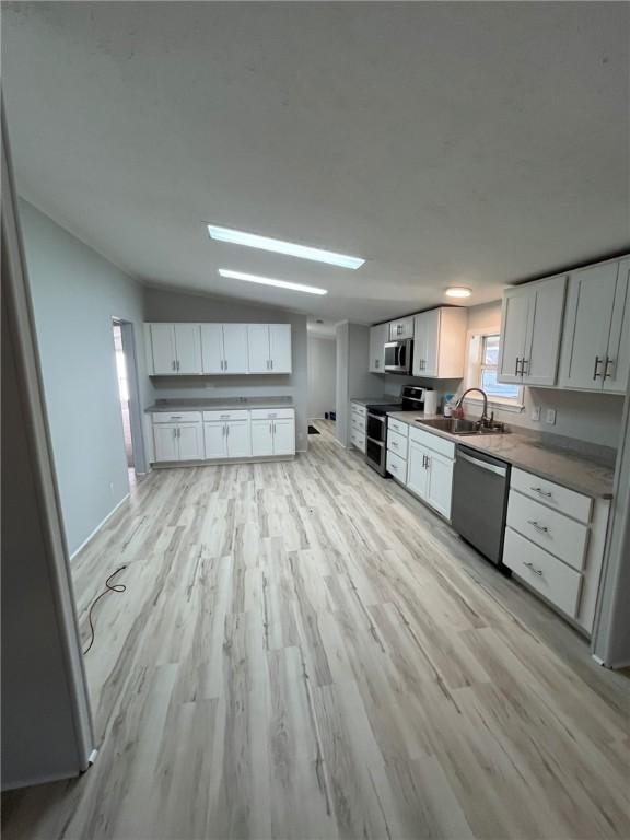kitchen featuring light wood-style flooring, appliances with stainless steel finishes, and white cabinetry