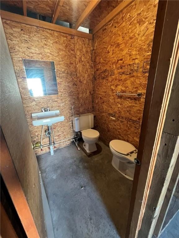 bathroom with toilet, a sink, and unfinished concrete floors